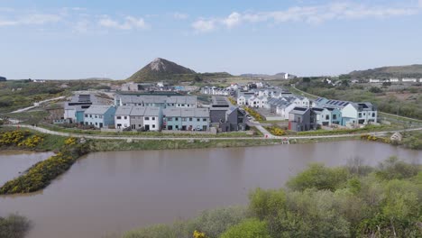 eco housing estate arranged around a tranquil retention pond, featuring white facades, solar roofs and pedestrian-friendly loops, contrasting pristine design with backdrop of reclaimed quarry mound