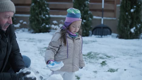 grandfather and granddaughter having fun in the snow