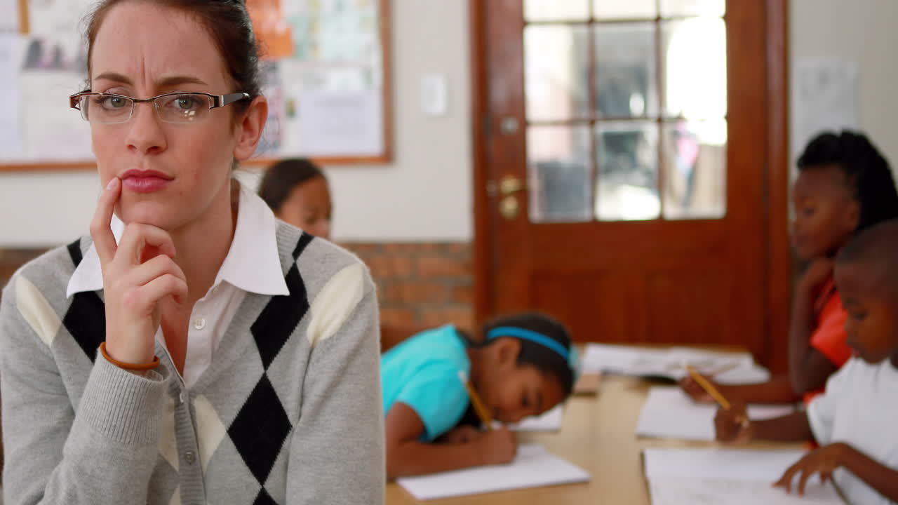 Thoughtful teacher looking at camera at top of classroom