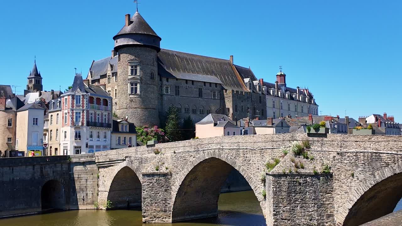 Walking view of the historic Pont Vieux aka Old Bridge with fortified medieval Laval Castle in the background, Laval, Mayenne, France.
