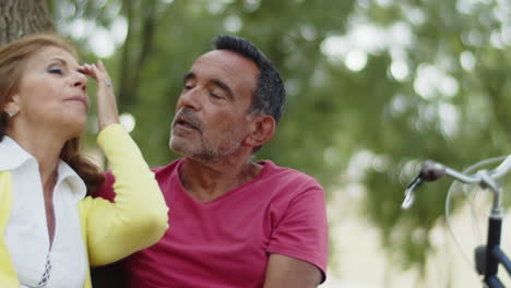 pareja de ancianos sentados juntos en el parque después de andar en bicicleta