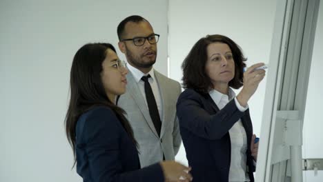 jóvenes trabajadores sonrientes hablando y dibujando a bordo en la oficina.