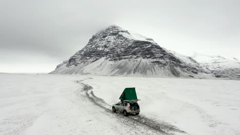 Schöner-Wohnmobilstellplatz-Mit-Komplett-Schneebedecktem-Island-Und-Einem-Berggipfel-Im-Hintergrund