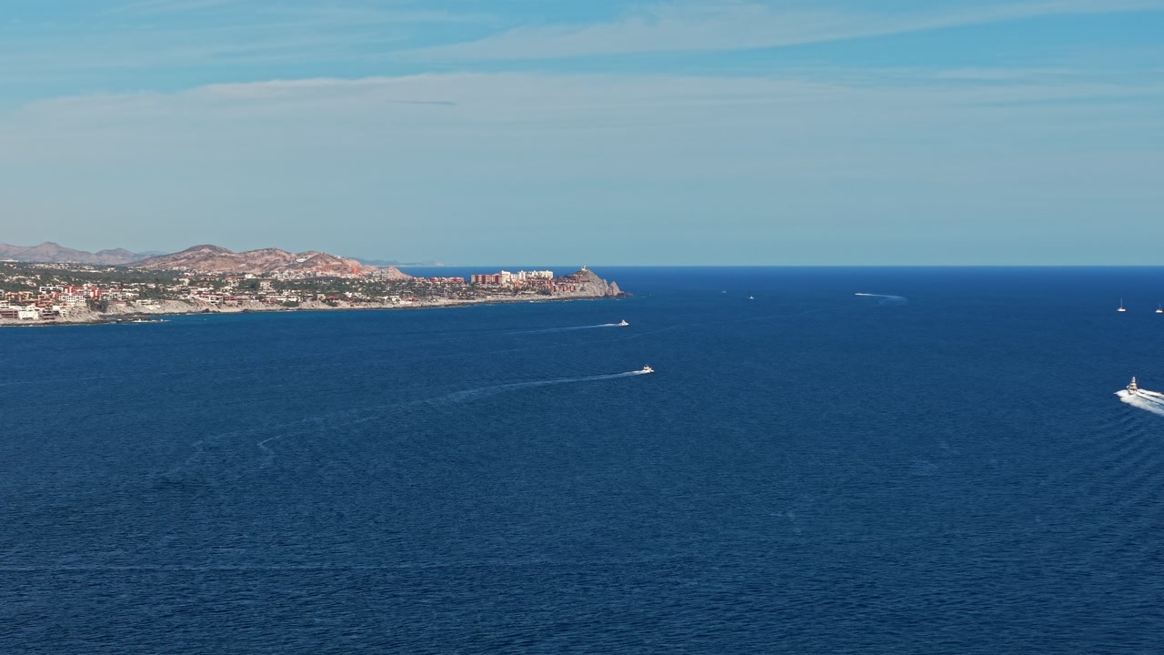 Telephoto aerial view of the coast of Los Cabos, with yachts sailing through the waters on a sunny day, Baja California, Mexico