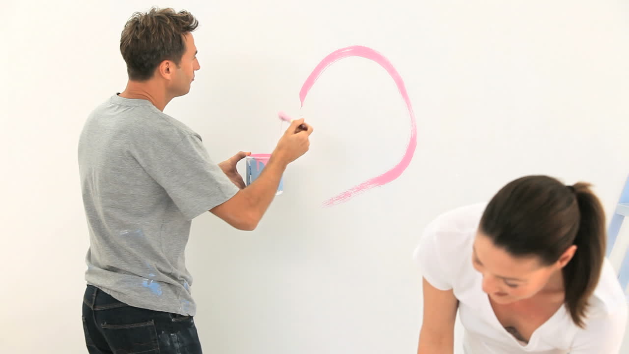 una pareja joven pintando una pared juntos.