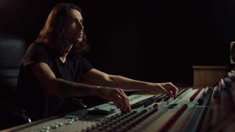 Thoughtful-man-working-in-music-studio.-Composer-moving-sliders-indoor.