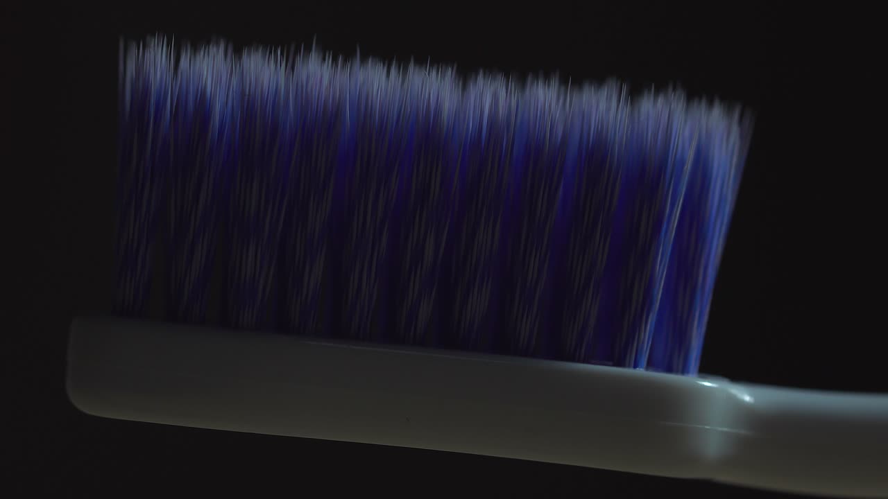 프레임의 극적인 서사시에서 희미하게 조명이 켜진 영역을 가로질러 가벼운 스와이프로 칫솔을 닫습니다.