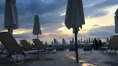 Empty-chairs-and-umbrellas-around-outdoor-swimming-pool-in-hotel-resort-after-rain-storm