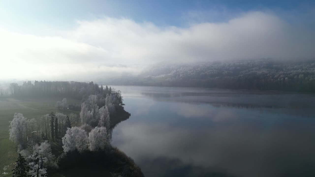 스위스의 평온한 겨울의 호수 위에서 구름이 물에 반사되어 있습니다.