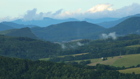 evaporación de nubes bajas sobre un paisaje montañoso lleno de colinas durante un día soleado después de una breve lluvia cuando el agua se evapora de los bosques circundantes