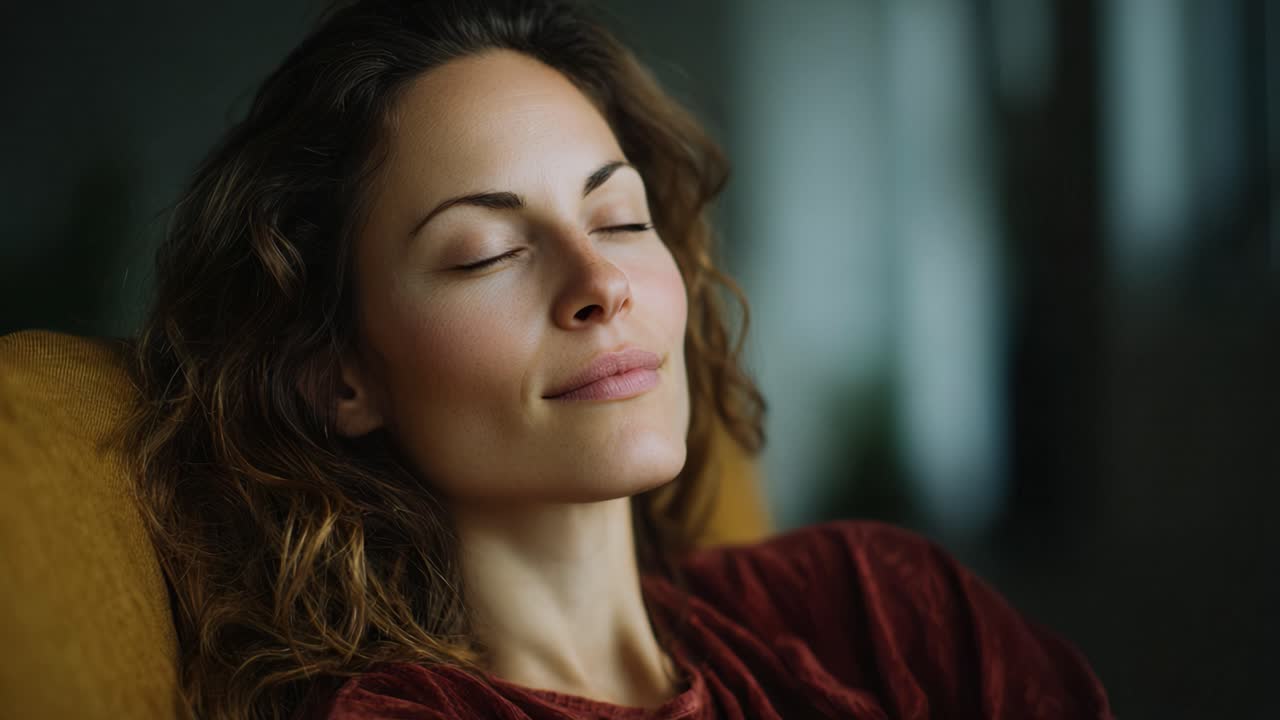 Una donna serena con gli occhi chiusi che si gode un momento di pace e relax, cogliendo l'essenza della tranquillità e della consapevolezza in un ambiente accogliente e invitante.