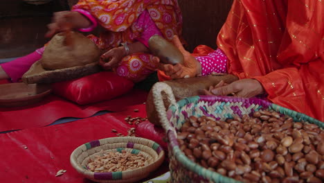 old women crushing argan nuts and producing argan oil from seeds