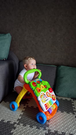 beautiful caucasian baby boy in white bodysuit pushes the toy by the floor. little child plays at home. vertical video.