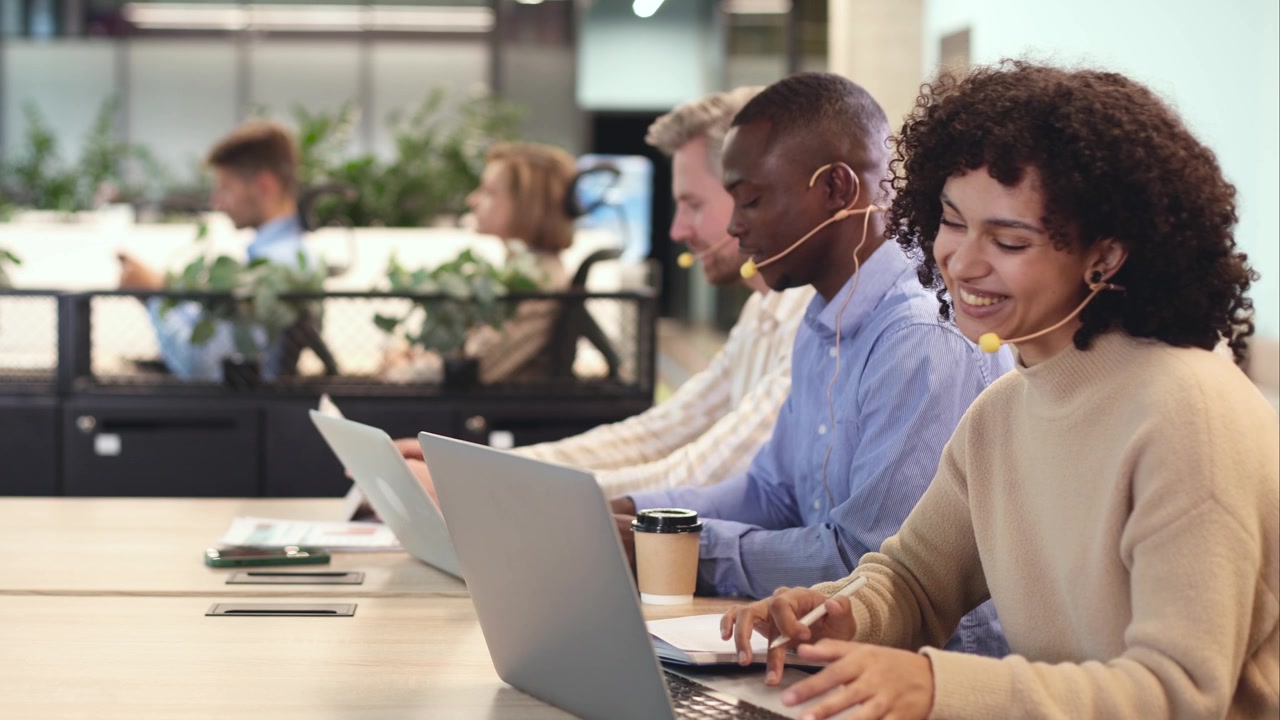 Team diversificato che lavora con portatili e cuffie in un ufficio moderno