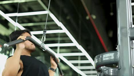 a man exercises on a lat pulldown machine in a well-lit gym, showcasing strength and focus