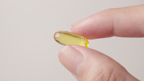 hand holding fish oil supplement yellow pill