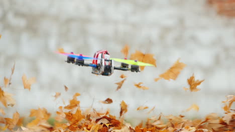 pilotando magistralmente un dron de película que vuela bajo sobre el suelo, las hojas secas vuelan lejos del viento lento m