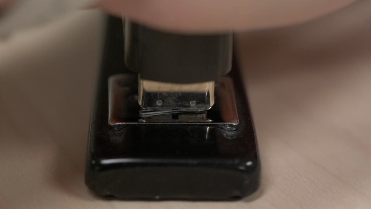 Tangan menekan stapler kosong berkali-kali hingga mengeluarkan isi stapler.