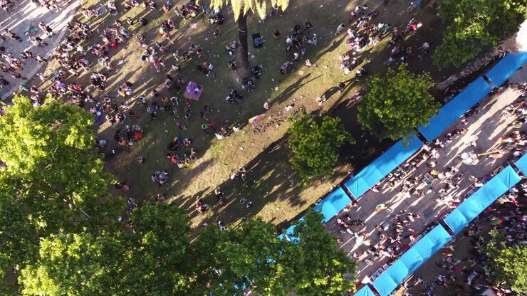 Aerial top down shot of people waving multicolored flags in park celebrating LGBT Pride Parade in Buenos Aires
