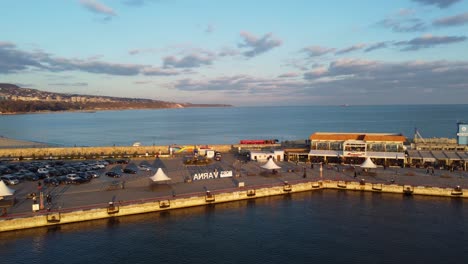 Puerto-De-Varna-Desde-Arriba-Con-Gente-Caminando-Y-Tiro-Al-Atardecer-Con-Drones