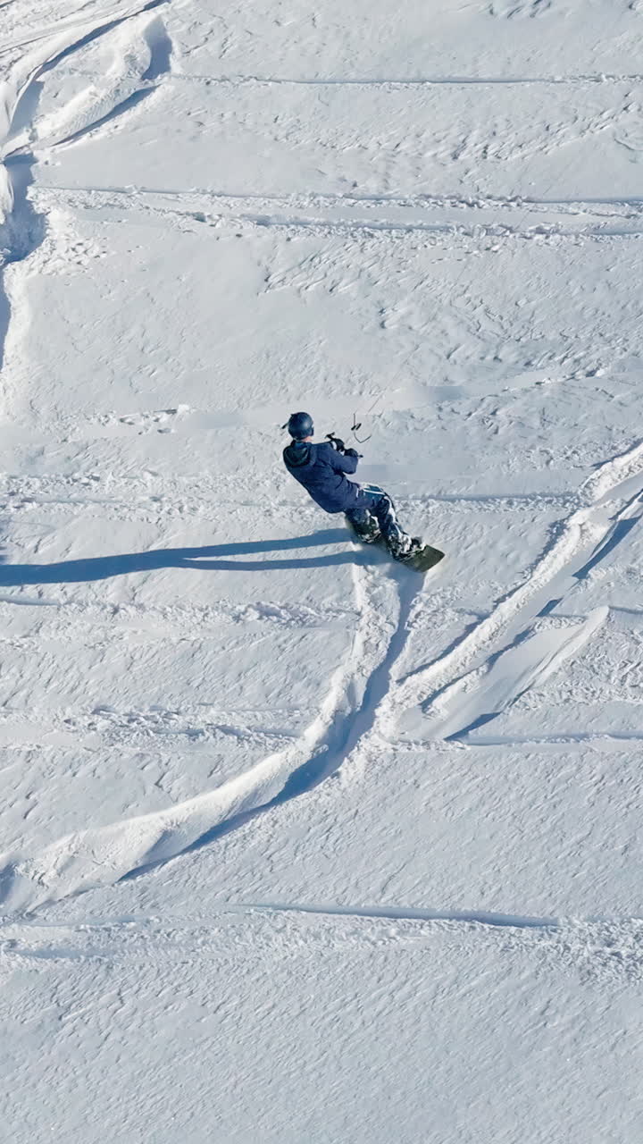 Aerial drone view of a sportsman snowkiting on the Giau Pass in the Dolomites, Italy. Vertical