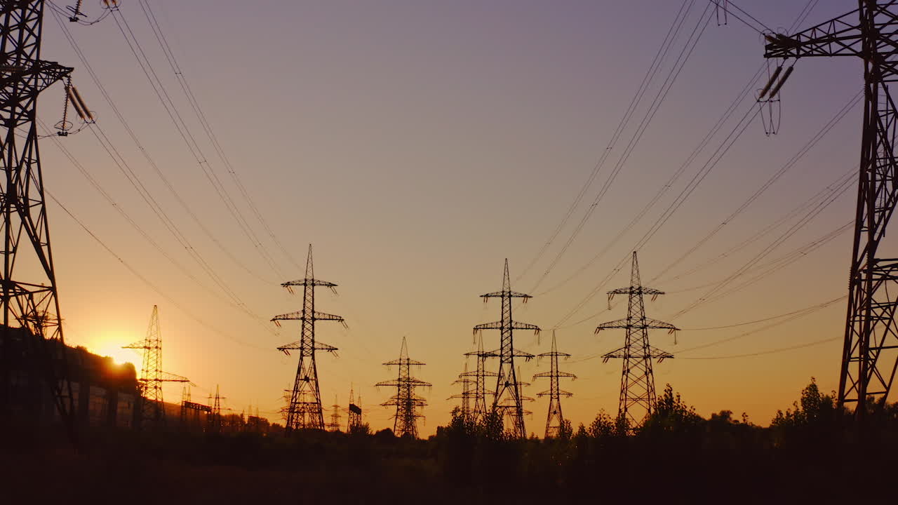 Silhouette of high-voltage towers. Electricity pylons on energy station on the background of beautiful sky at sunset. Electricity station and high-voltage power lines.View from below.