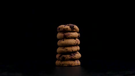 pila de bellamente galletas vegetarianas, galletas doradas con chocolate girando contra un fondo negro, tiro estático