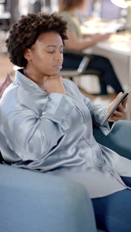 vertical video of african american casual businesswoman using tablet in office, slow motion