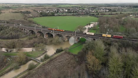 Vista-Aérea-Del-Viaducto-De-Haversham-Y-Little-Linford-Con-Trenes-De-Carga-Y-Pasajeros-Que-Lo-Cruzan,-Milton-Keynes,-Buckinghamshire,-Inglaterra