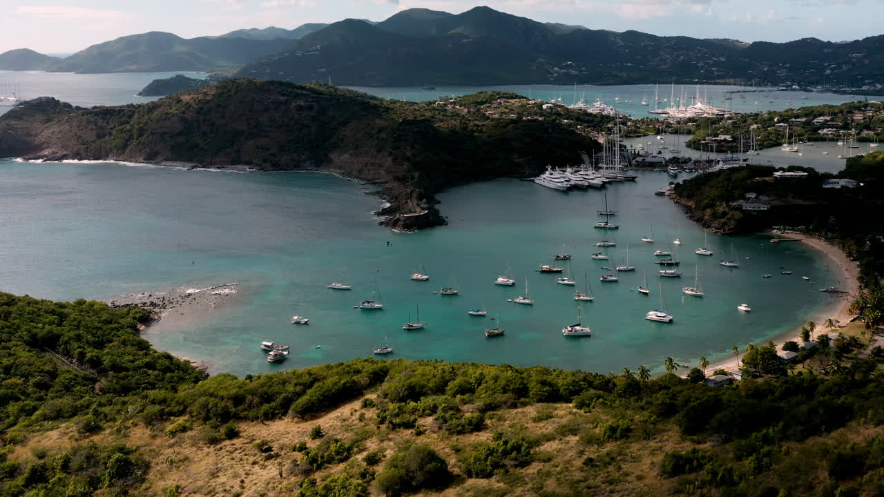 toma aérea de la puesta de sol en puerto inglés en antigua, caribe con vistas de yates, veleros, puerto deportivo, bahía y acantilados