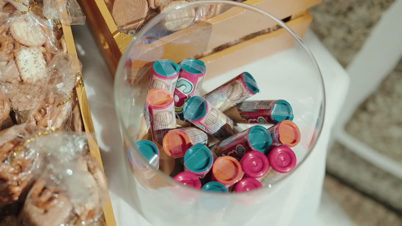 candy poppers with pink orange blue caps in a clear bowl beside packaged cookies on display