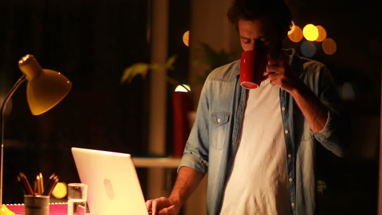 Manager che beve un caffè mentre lavora al laptop