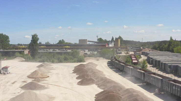 Aggregate Extraction Industrial Zone With Stockpile And Freight Train Cars. - aerial shot