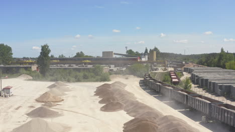 aggregate extraction industrial zone with stockpile and freight train cars. - aerial shot