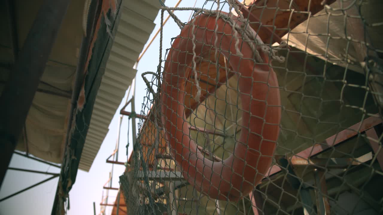 Orange lifebuoy hanging on a wire fence