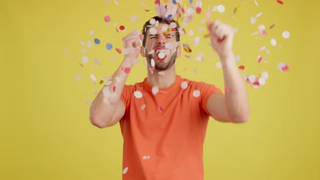 joyful man celebrating with confetti on yellow background
