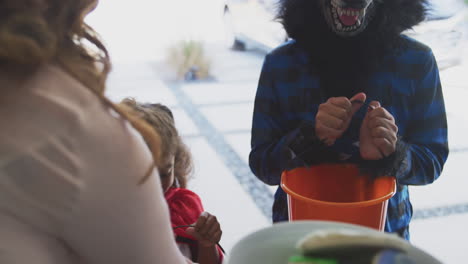 Two-Children-In-Fancy-Dress-Outside-House-Collecting-Cookies-For-Trick-Or-Treat-From-Grandparents