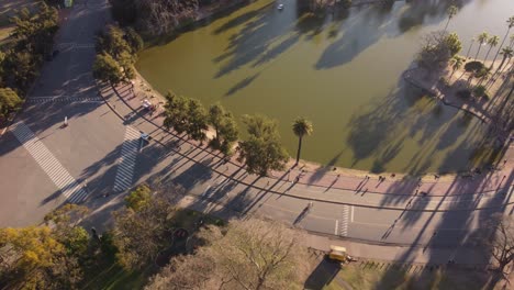 Aerial-view-of-sporty-people-walking-and-riding-bike-on-promenade-of-Park-with-Lake-in-Buenos-Aires