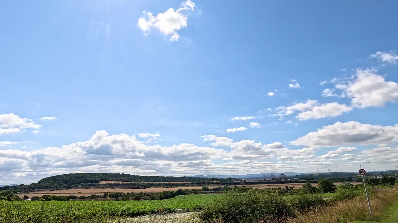 Sunny summer drive along winding rural road, green fields, blue sky, dynamic forward camera movement