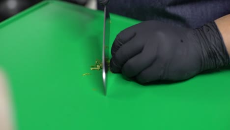 chef hands cutting parsley on a green cutting board, close up