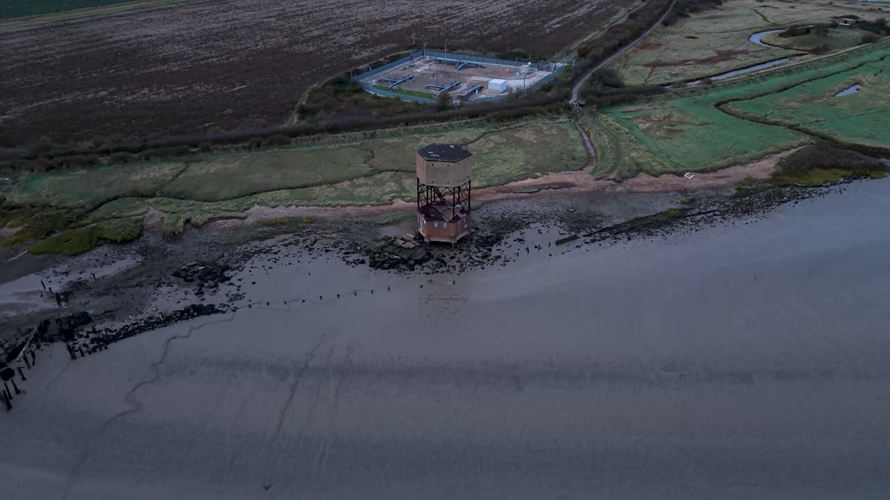 East Tilbury radar tower aerial view rising over River Thames marshland foreshore
