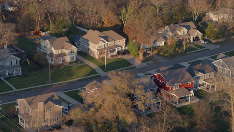 flyover nice neighborhood with autumn trees at peak color at golden hour