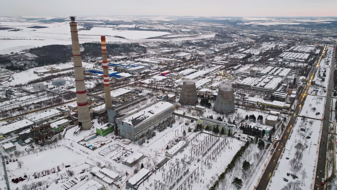 Aerial drone view of a working thermal power station in Chisinau city, covered in snow. Steam and smoke coming from pipes during winter in Moldova