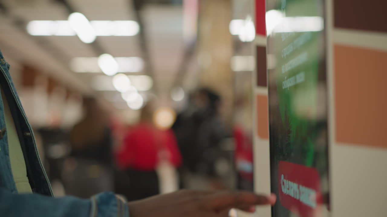 Close-up of hand pointing at menu on digital screen, selecting food options in self-service kiosk. Menu features food items like burgers and fries, with colorful buttons and interface visible