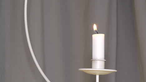 unrecognizable male hand lights a hanging candle on dark curtain background, smoke rises and disperse