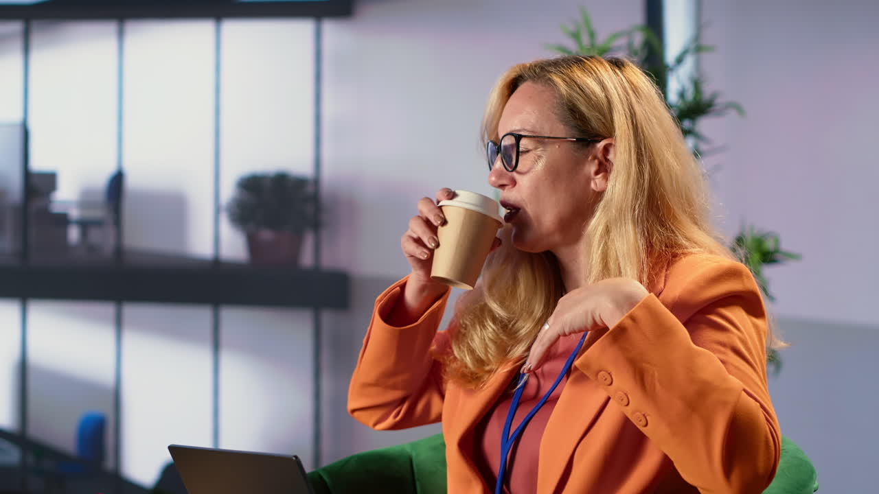 mujer de negocios trabajando en una computadora portátil y bebiendo café en la oficina