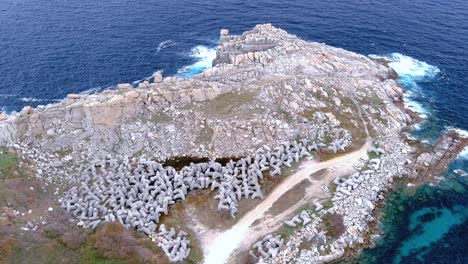 aerial backward moving shot of paper cliffs along hilly terrain surrounded by sea water in the area of morás, xove, lugo, galicia, spain