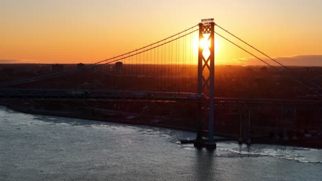 ambassador bridge at sunset with golden light reflecting on the detroit river