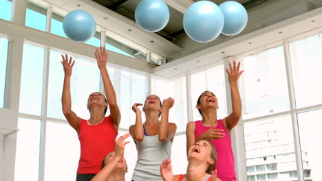 fitness class smiling at camera throwing exercise balls