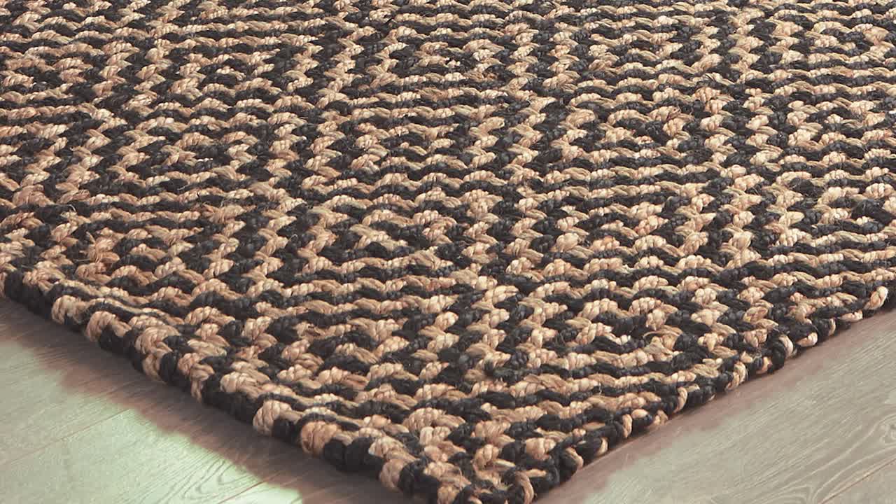 Camera sweeps over patterned rug resting on polished wood boards